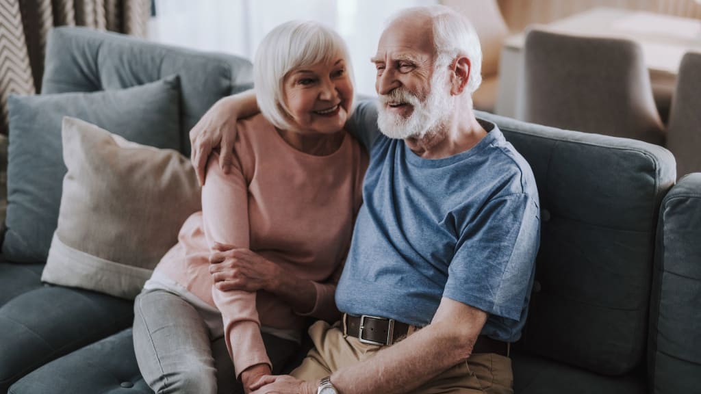Happy elder couple embracing on sofa at home